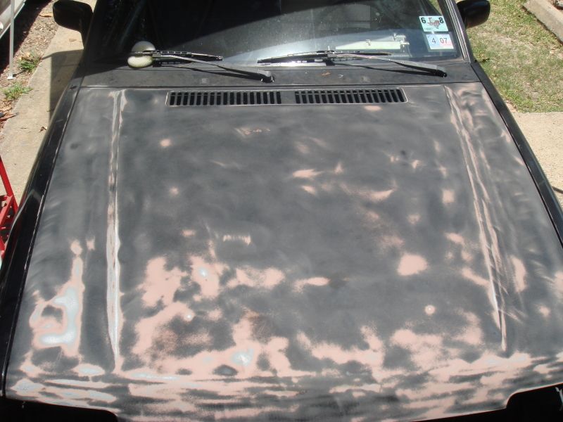 Car hood with primer showing through worn paint, windshield wipers visible