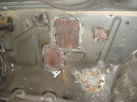 1989 Ford Escort - This photo shows several metal patches that have been welded onto the floor pan of a vehicle.