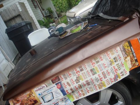 1989 Ford Escort - Car hood undergoing preparation for painting, with various tools and materials laid out.
