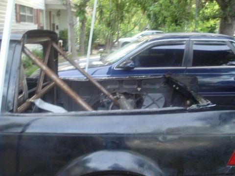 1989 Ford Escort - Roll cage structure inside a vehicle, with another car parked behind it.