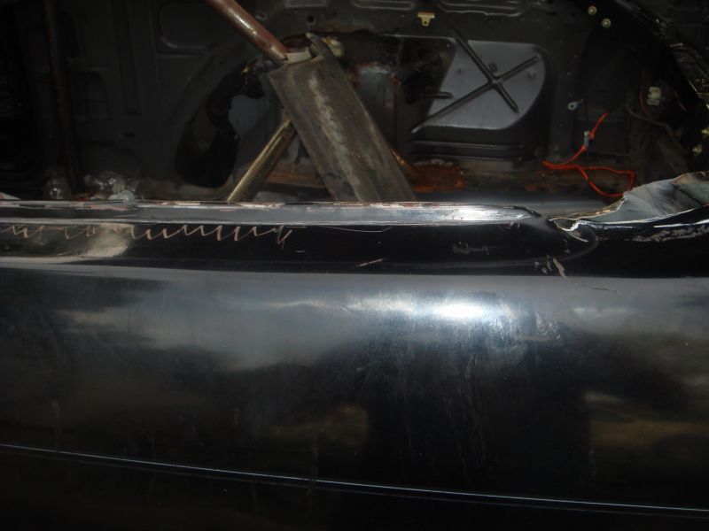 Black car interior with roll cage, exposed metal, and wiring