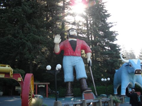 1991 Ford Bronco - A roadside attraction features a giant lumberjack statue waving hello, accompanied by a blue ox statue.