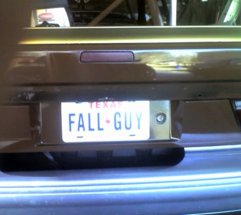 1989 Ford Escort - The rear of a car displays a Texas license plate with the custom text "FALL GUY".