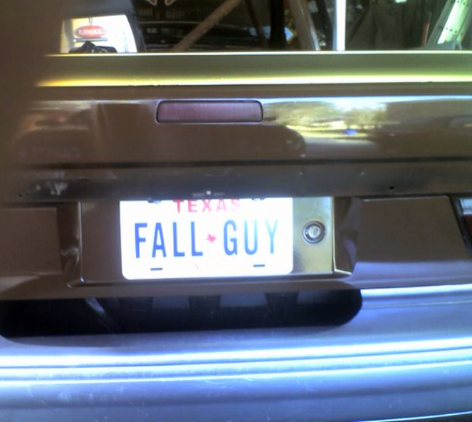 Rear of a car with a Texas license plate reading "FALL GUY"