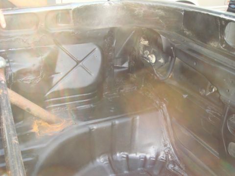 1989 Ford Escort - The interior floor of a car shows some rust on a metal bar and appears to be undergoing some work.