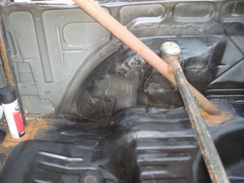 1989 Ford Escort - The interior of a car trunk shows black undercoating and a roll bar, with a spray paint can visible.