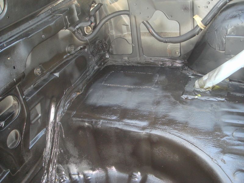 Interior of car trunk area with black undercoating and wiring