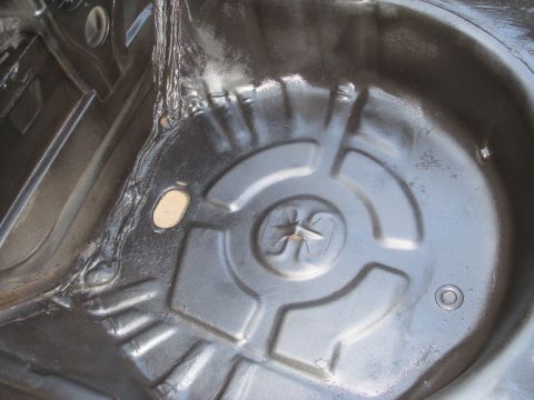 1989 Ford Escort - Underside of a car's spare tire well, showing the metal stamping and undercoating.