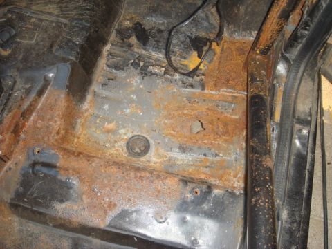 1989 Ford Escort - The interior floor pan shows significant rust and exposed metal, indicating a need for repair.