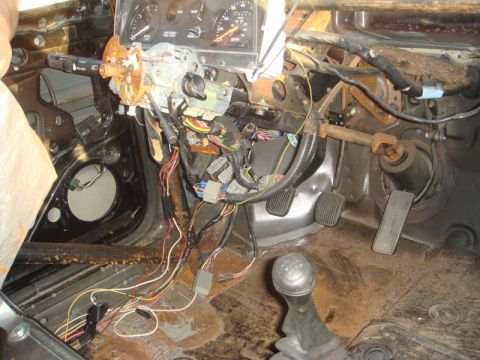 1989 Ford Escort - The dashboard and center console are disassembled, revealing the vehicle's internal wiring and components.