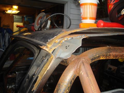 1989 Ford Escort - Angle grinder sits on a heavily rusted car roof, revealing a roll cage and damaged metalwork.