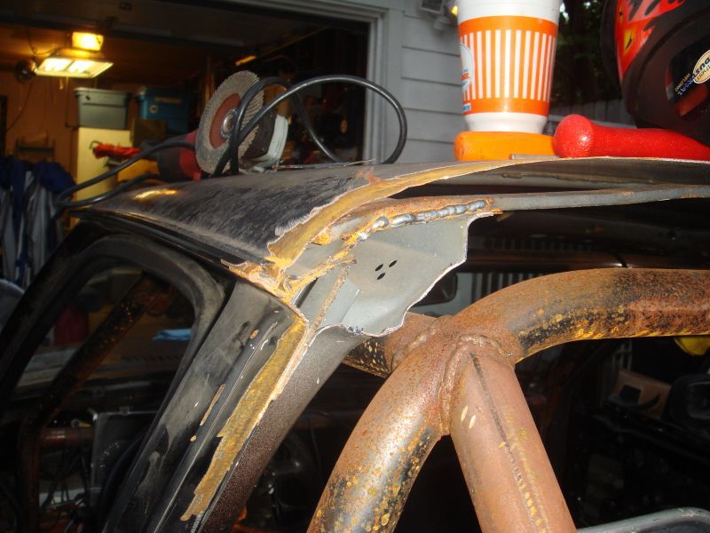 Rusted car roof section with roll cage and angle grinder