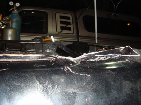1989 Ford Escort - Welding sparks fly over a damaged car hood, with a truck cap visible behind it.