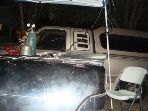1989 Ford Escort - Welding equipment is set up on the bed of a black truck, with a silver pickup truck visible behind it.