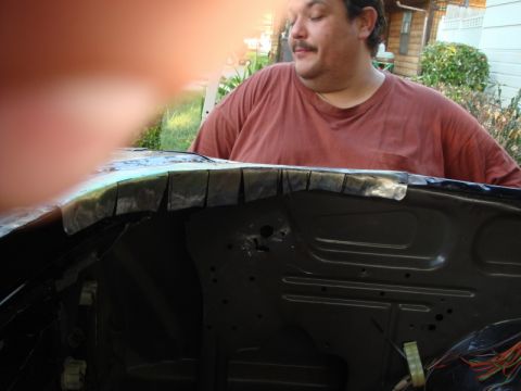 1989 Ford Escort - A man stands behind the cut edge of a car's engine bay, with a house and greenery in the background.