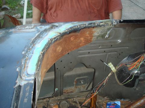 1989 Ford Escort - A person is welding a car's fender, showing rust and exposed wiring.