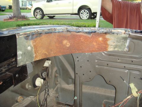 1989 Ford Escort - Close-up view of a car's engine bay showing repair work on a rusted metal panel.