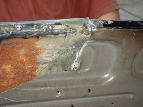 1989 Ford Escort - Close-up of a rusted metal panel showing recent welding work.