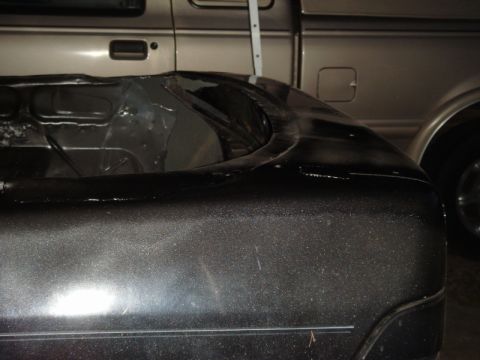 1989 Ford Escort - Detail of a car's fender next to a pickup truck.