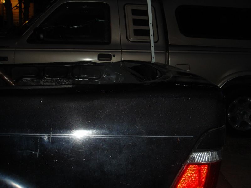 Rear of dark car with silver truck behind it