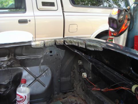 1989 Ford Escort - Work in progress on a car's engine bay, with a pickup truck and welding mask in the background.