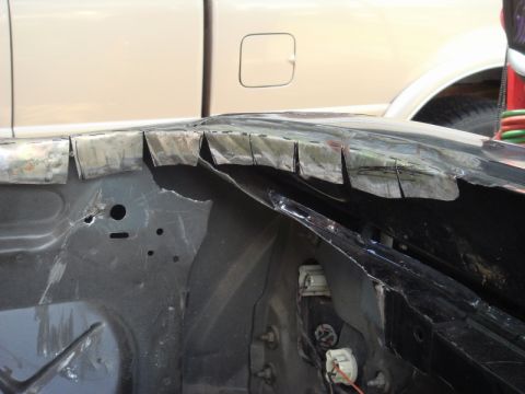 1989 Ford Escort - The front fender of a car is being cut and prepared for bodywork, with another vehicle visible behind it.