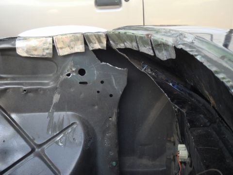 1989 Ford Escort - Close-up of a car's fender well showing cut metal and exposed components.