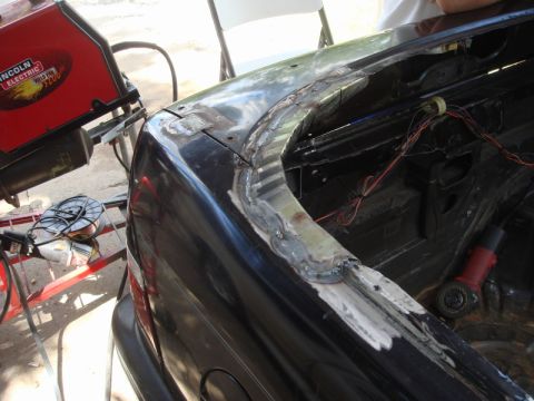 1989 Ford Escort - Bodywork is underway on a dark-colored vehicle, with welding and grinding equipment present.