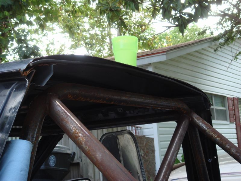 Interior view of a vehicle with a rusty roll cage and a green cup on the roof