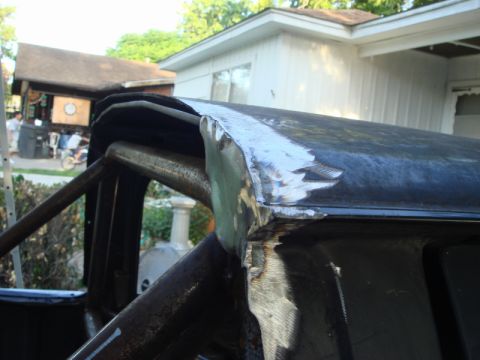 1989 Ford Escort - Close-up view of welding work being done on the roof of a vehicle, with a house and trees in the background.