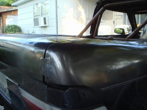 1989 Ford Escort - The rear bed of a pickup truck shows damage and a custom roll cage structure.