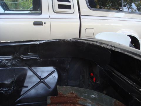 1989 Ford Escort - The underside of a car is shown with a silver pickup truck partially visible behind it.