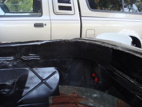 1989 Ford Escort - The image shows a close-up of a vehicle's frame, with a portion of a pickup truck visible in the background.