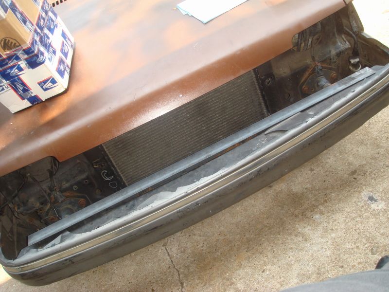 1989 Ford Escort front end with rusty hood, radiator, and bumper