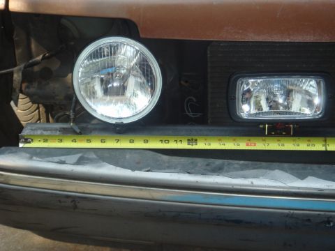 1989 Ford Escort - Measuring headlights, one round and one rectangular, with a tape measure.