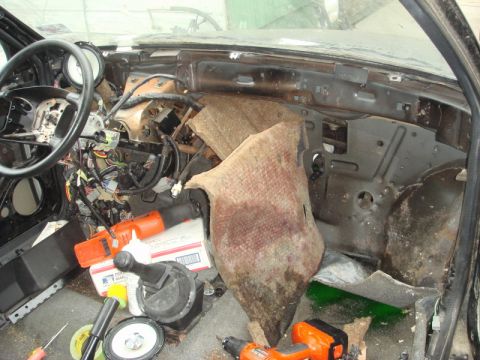 1989 Ford Escort - The interior of a vehicle shows a disassembled dashboard with exposed wiring and various tools scattered around.