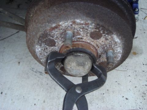 1989 Ford Escort - Pliers are used to remove a ball joint from a corroded brake drum assembly.