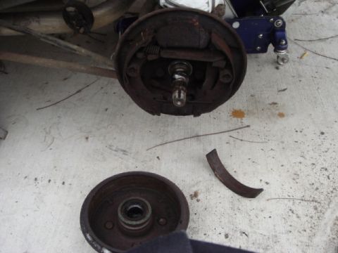 1989 Ford Escort - The brake drum and assembly are shown removed from the vehicle, with a piece of the drum broken off.