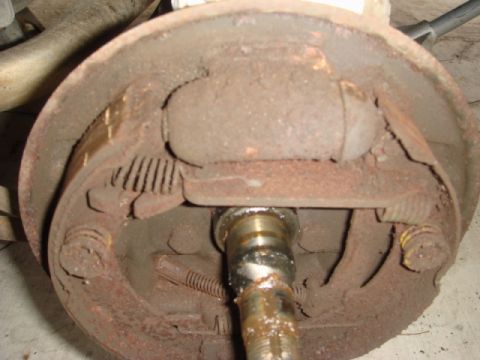 1989 Ford Escort - This image shows a close-up view of a rusty brake drum assembly, highlighting its internal components like springs and metal parts.