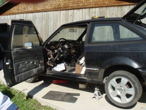 1989 Ford Escort - This black Ford Escort appears to be undergoing repairs, with its interior stripped bare.