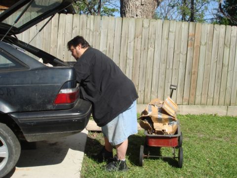 1989 Ford Escort - A person loads items into the trunk of a dark 1989 Ford Escort hatchback.
