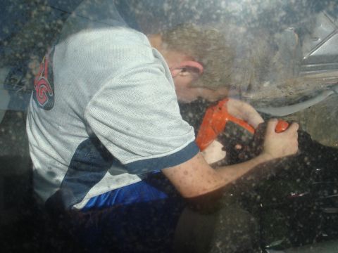 1989 Ford Escort - A person is seen from outside the vehicle, working on the interior with an orange tool.