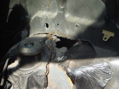 1989 Ford Escort - This image shows significant rust and damage to a vehicle's chassis, obscuring any specific year identification.