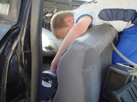 1989 Ford Escort - A young person is focused on working inside a vehicle's cabin with a diagnostic tool.
