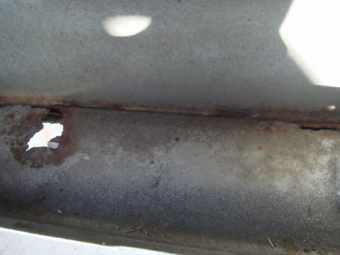 1989 Ford Escort - Detail of rusted metal, possibly from a vehicle's undercarriage, showing significant corrosion and a hole.