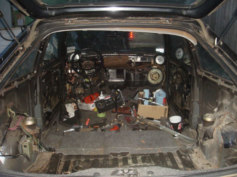 Gutted hatchback interior shot from the rear hatch, bare floor pan and loose parts