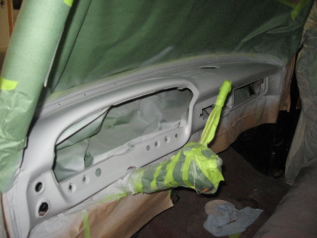 Dashboard of a vehicle covered in masking tape and paper, ready for paint. The steering column is also taped