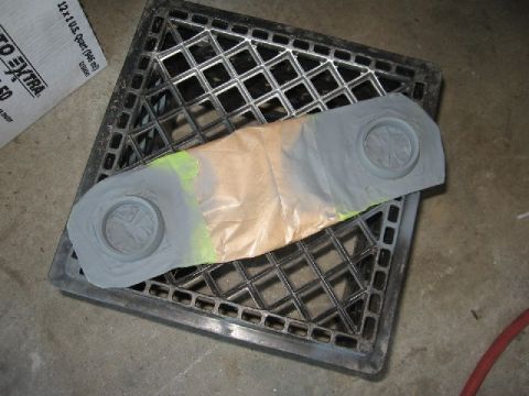 1966 Ford F-100 - A taped automotive part is being painted while resting on a black plastic crate.