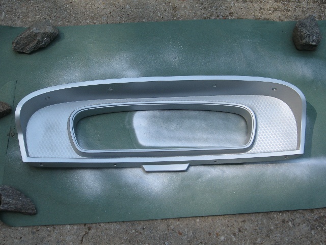 Silver instrument cluster bezel with textured inner surface, resting on a green mat