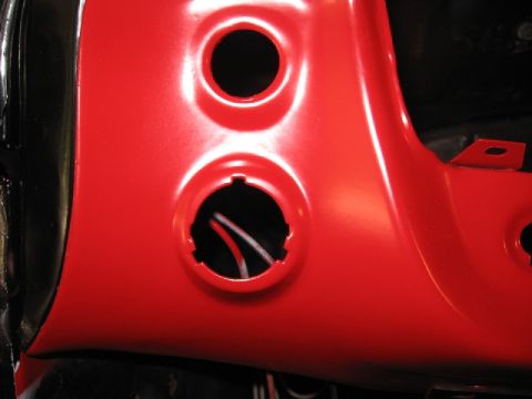 1966 Ford F-100 - Close-up of a red dashboard panel showing two circular cutouts for gauges or switches.